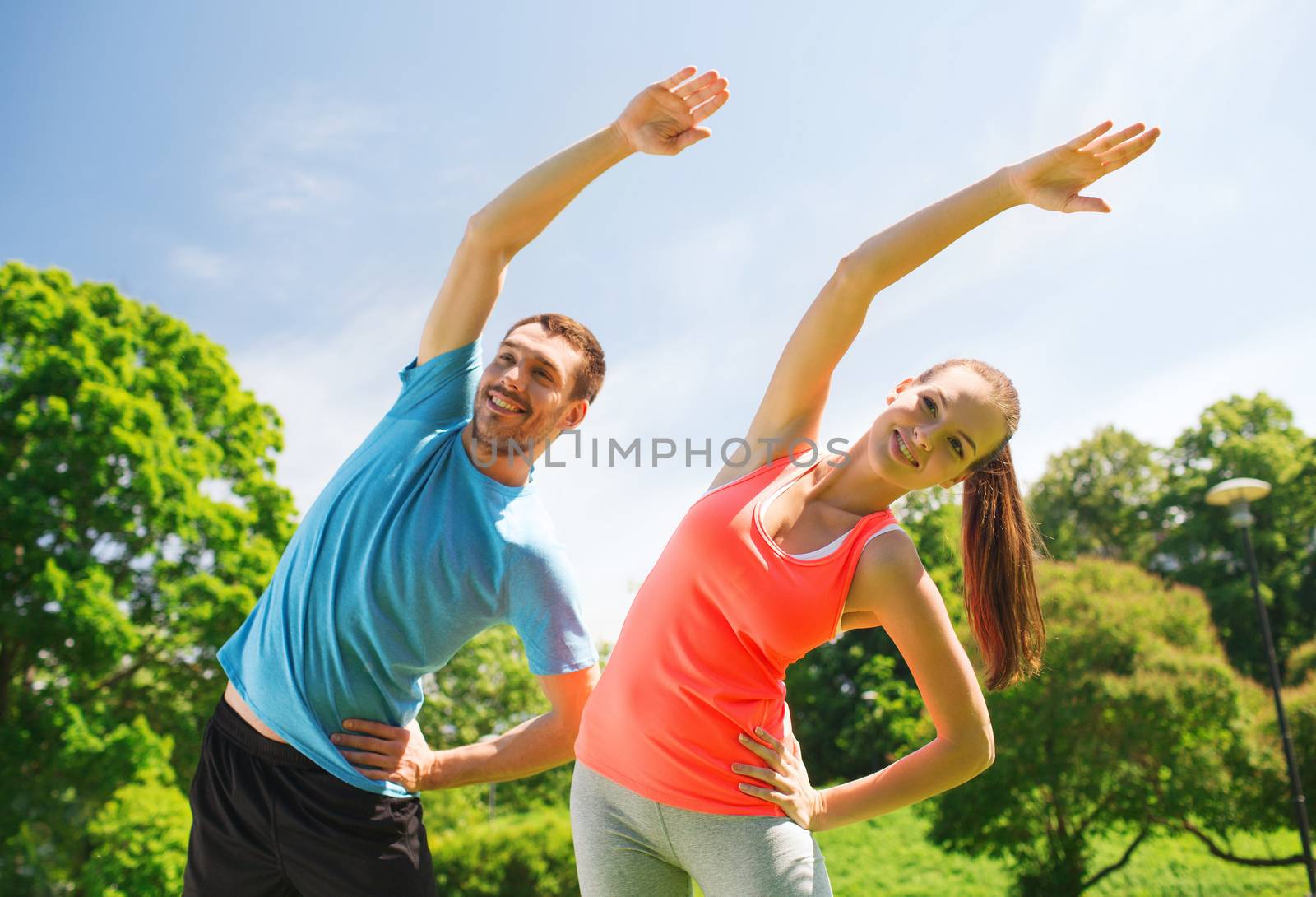smiling couple stretching outdoors by dolgachov