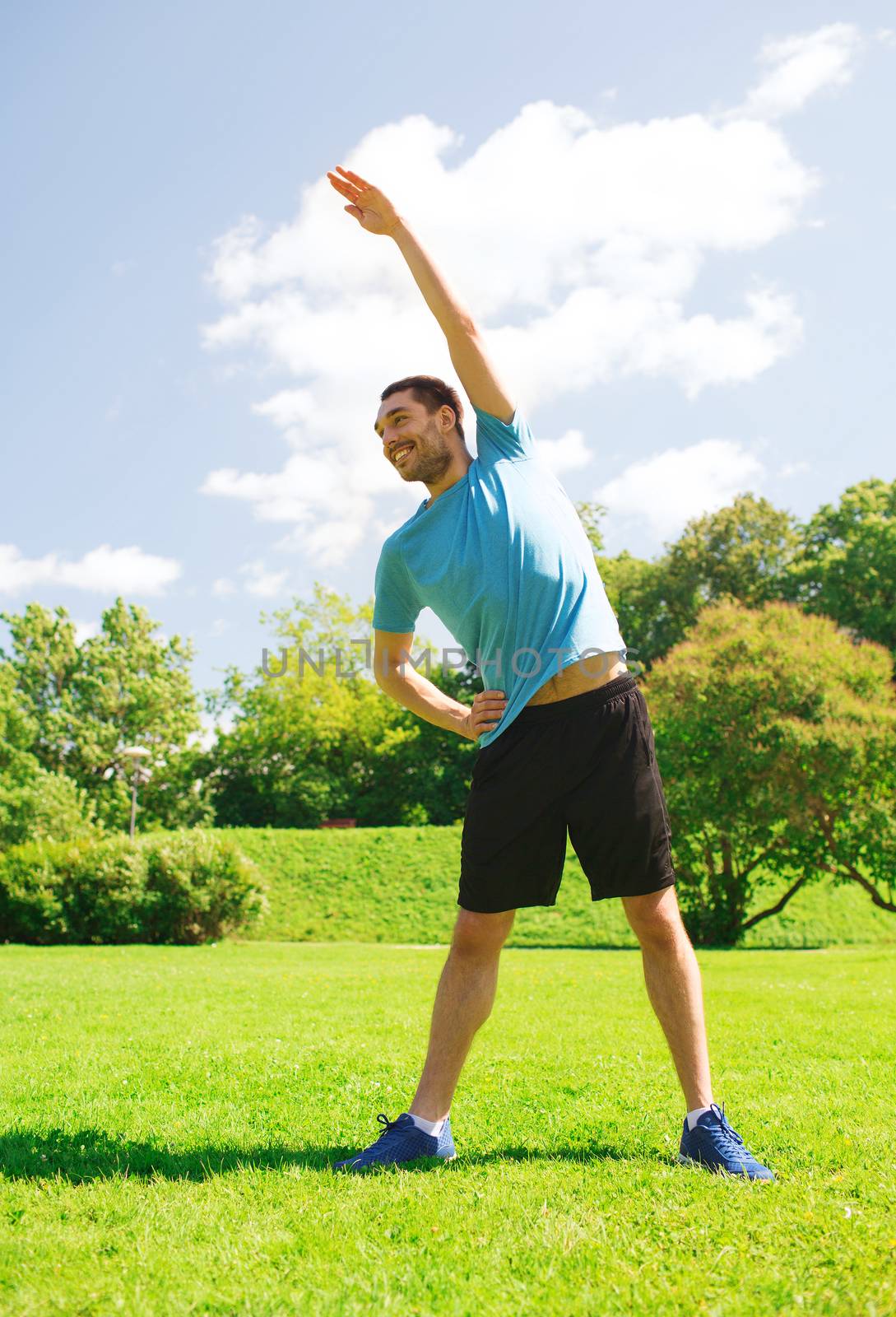 smiling man stretching outdoors by dolgachov