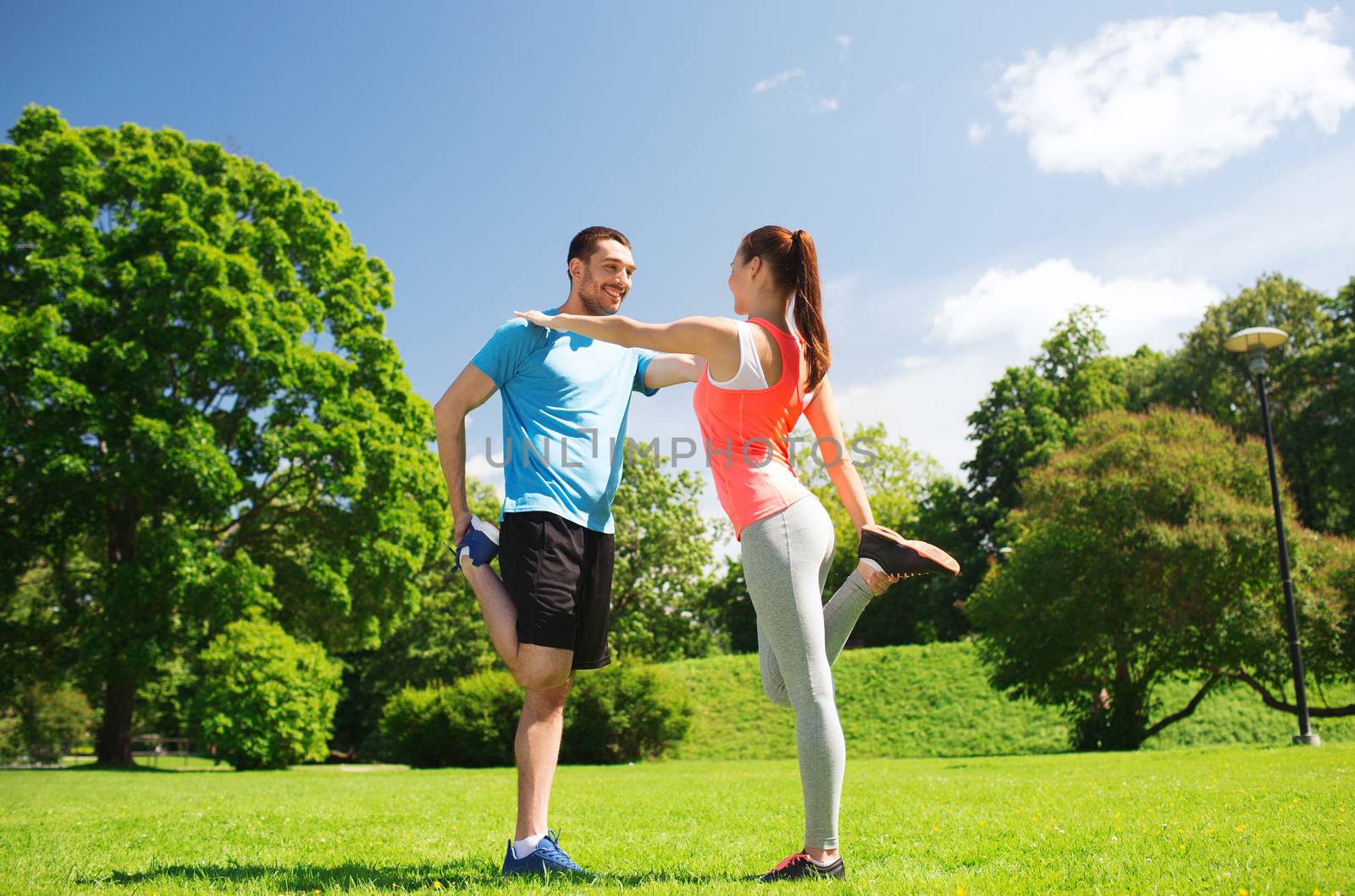 fitness, sport, training and lifestyle concept - smiling couple stretching outdoors