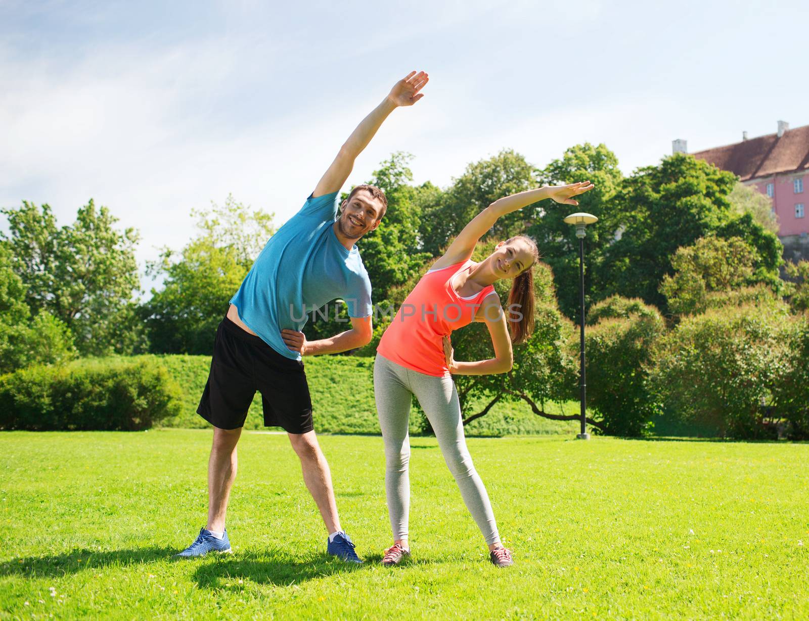 smiling couple stretching outdoors by dolgachov