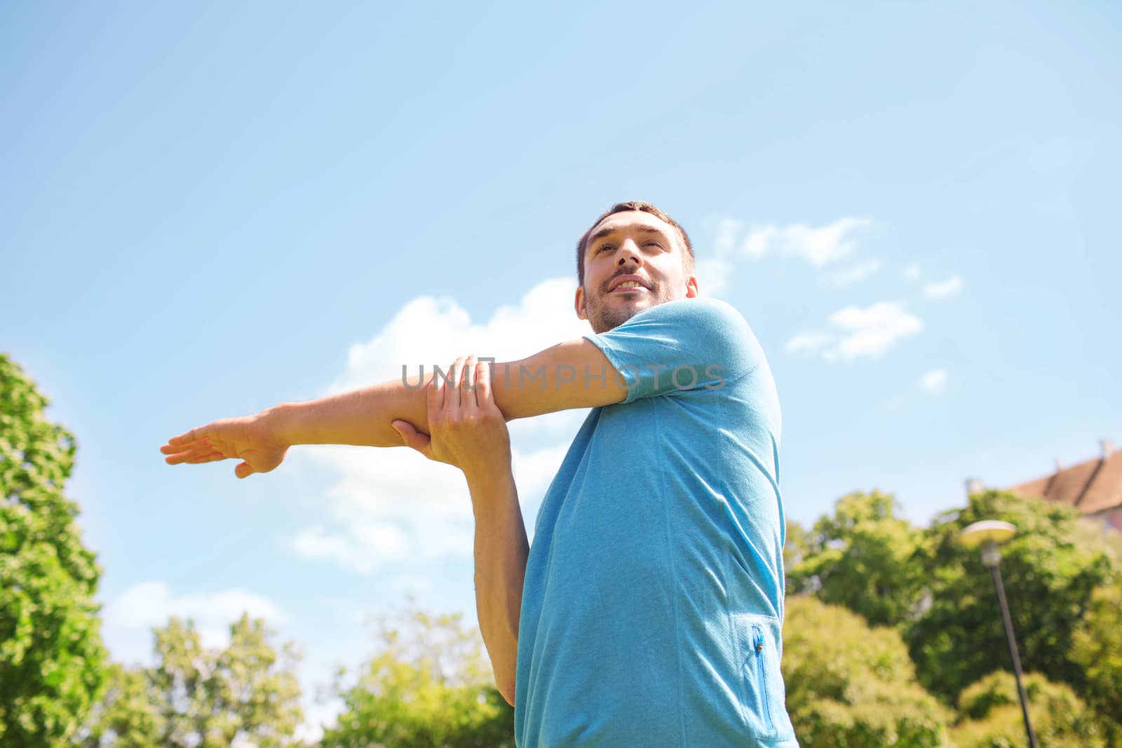 smiling man stretching outdoors by dolgachov