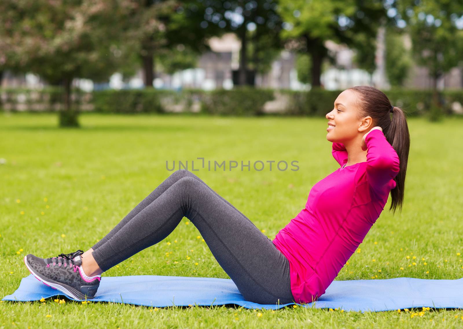 smiling woman doing exercises on mat outdoors by dolgachov