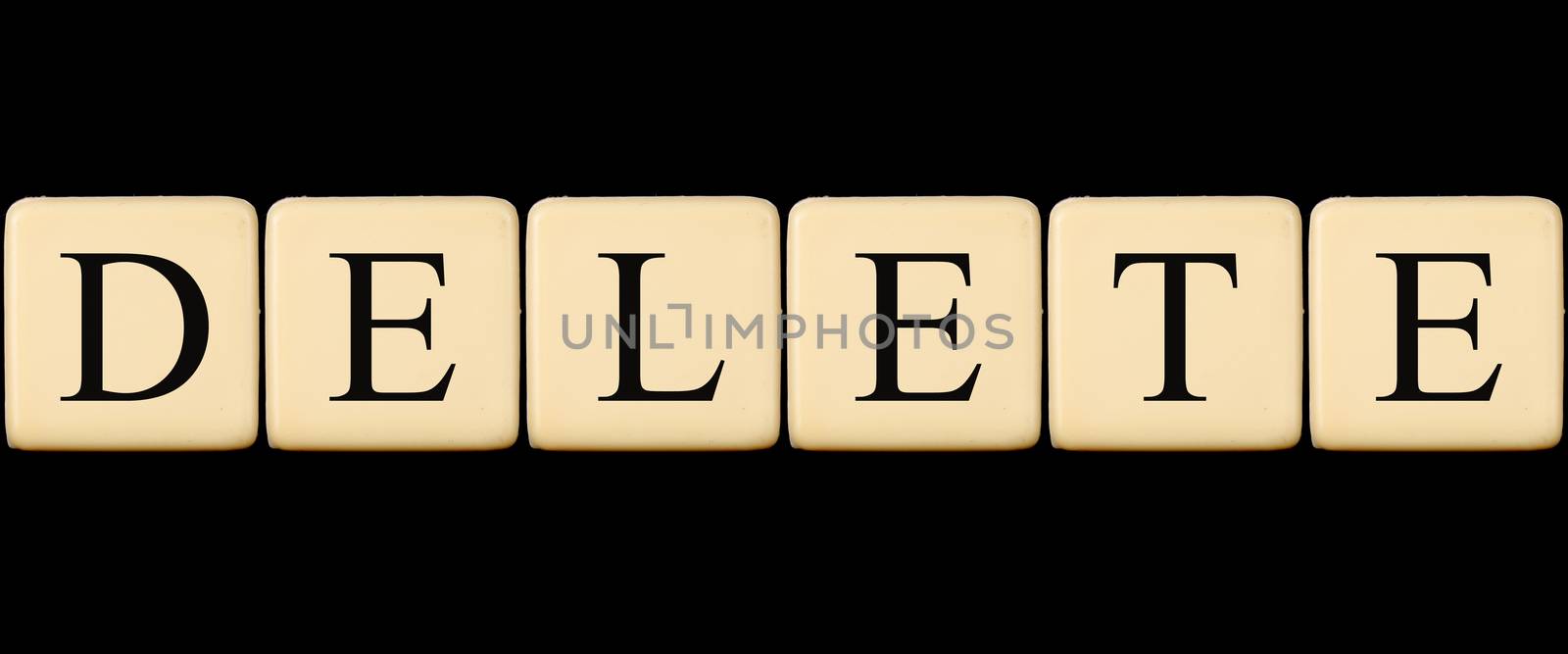 A delete word made from scrabble tiles, on black studio background.
