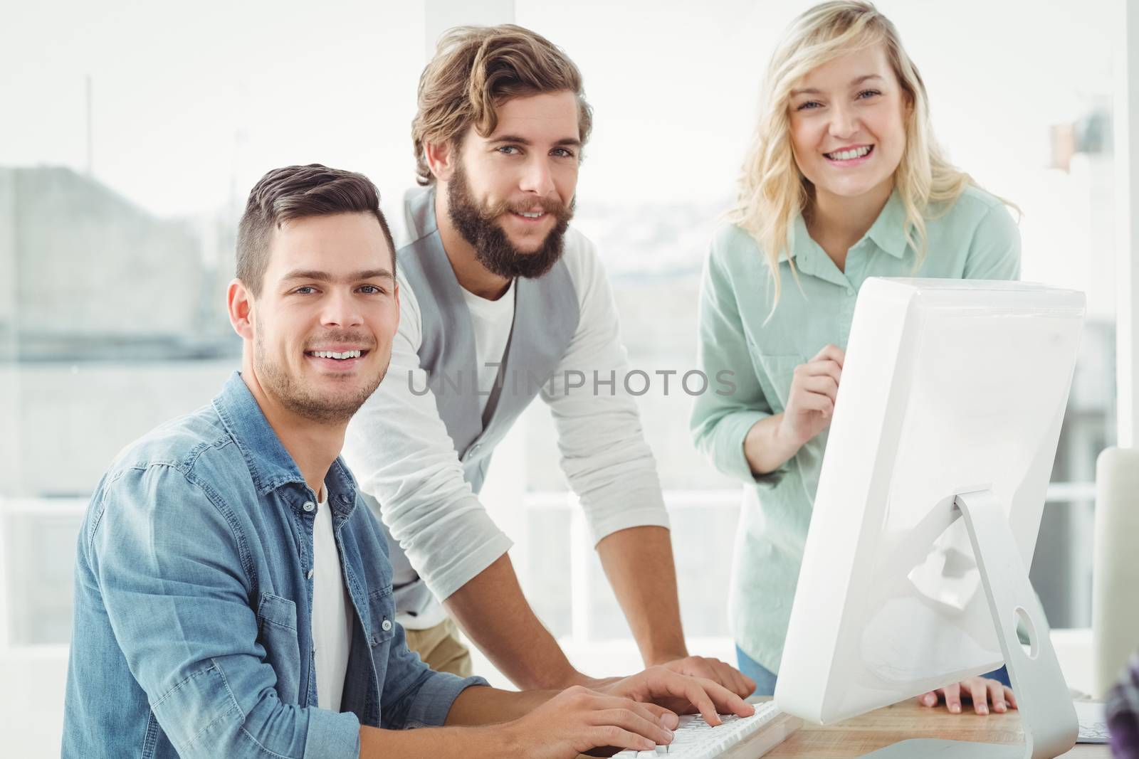 Portrait of business professionals discussing at computer desk in office