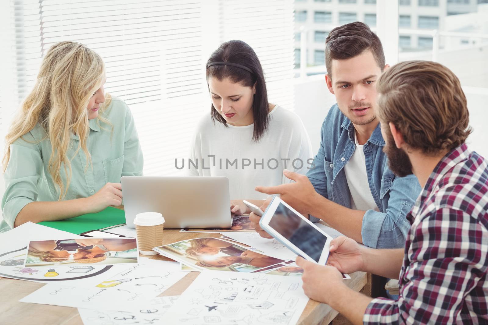 Creative business professionals discussing while sitting at desk in office