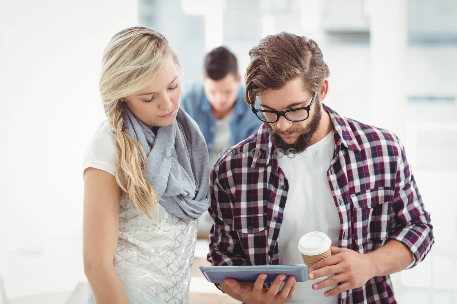 Man and woman working on digital tablet at desk in office