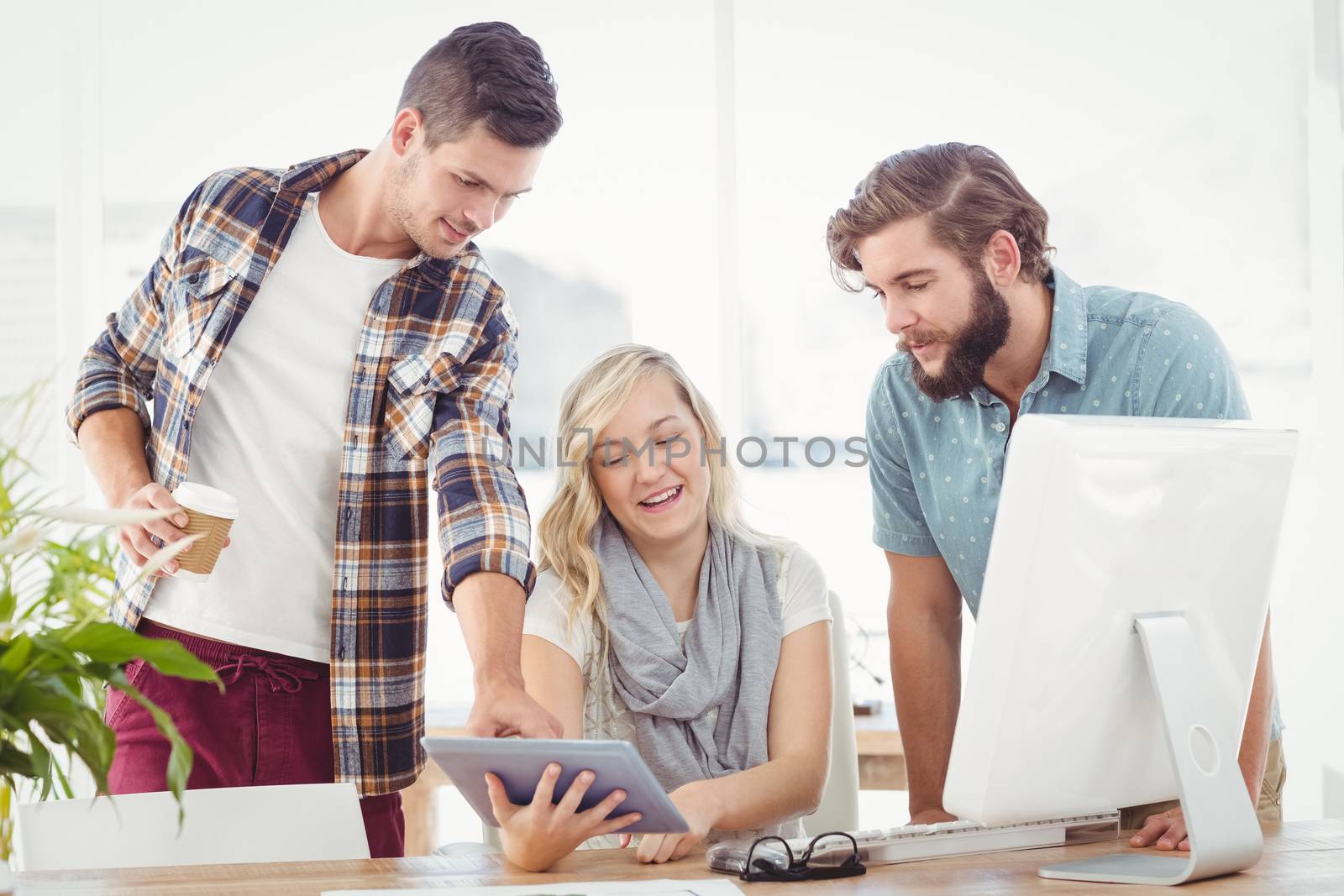 Business professionals using digital tablet while sitting at desk in office