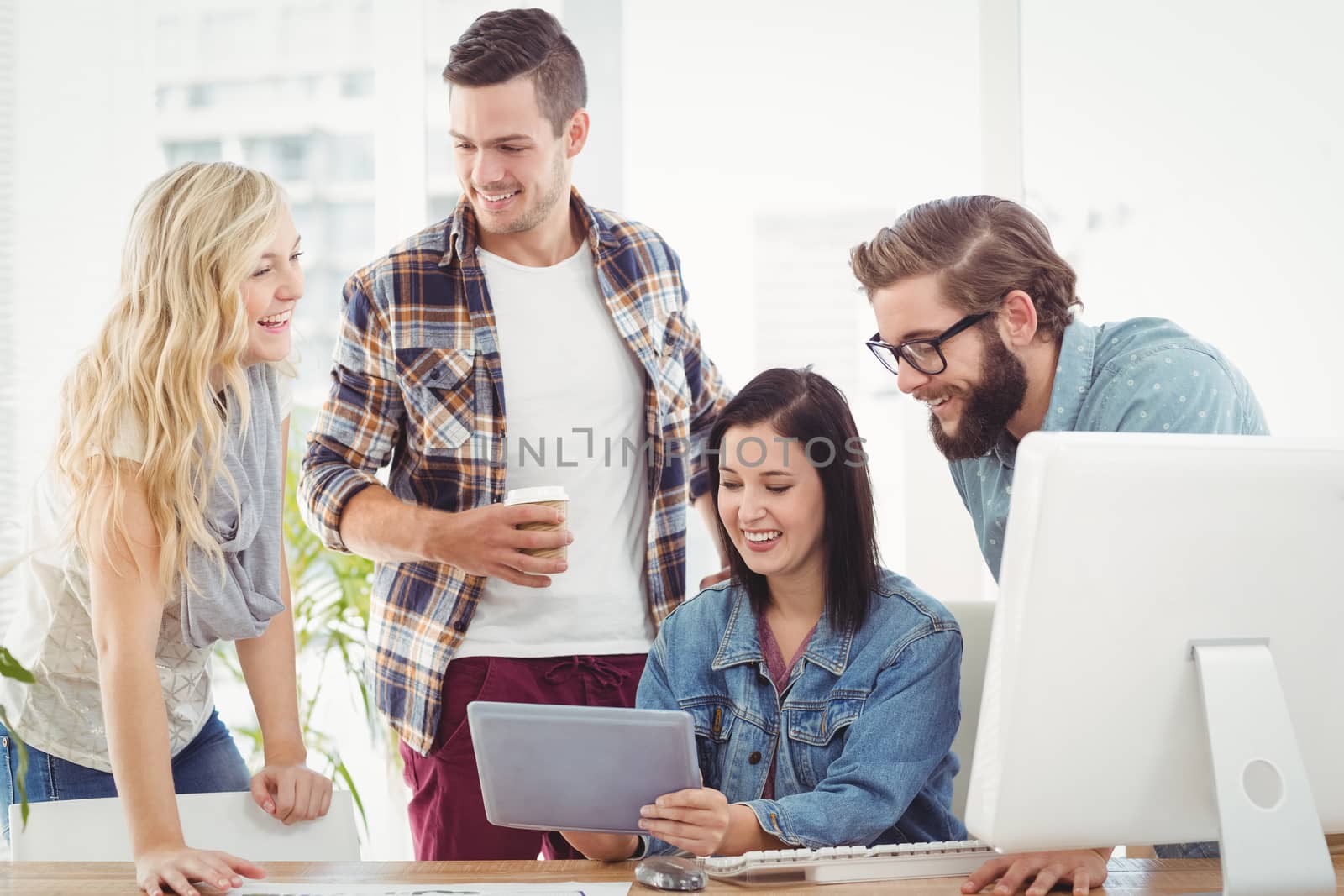 Smiling Business professionals using digital tablet while sitting at desk in office