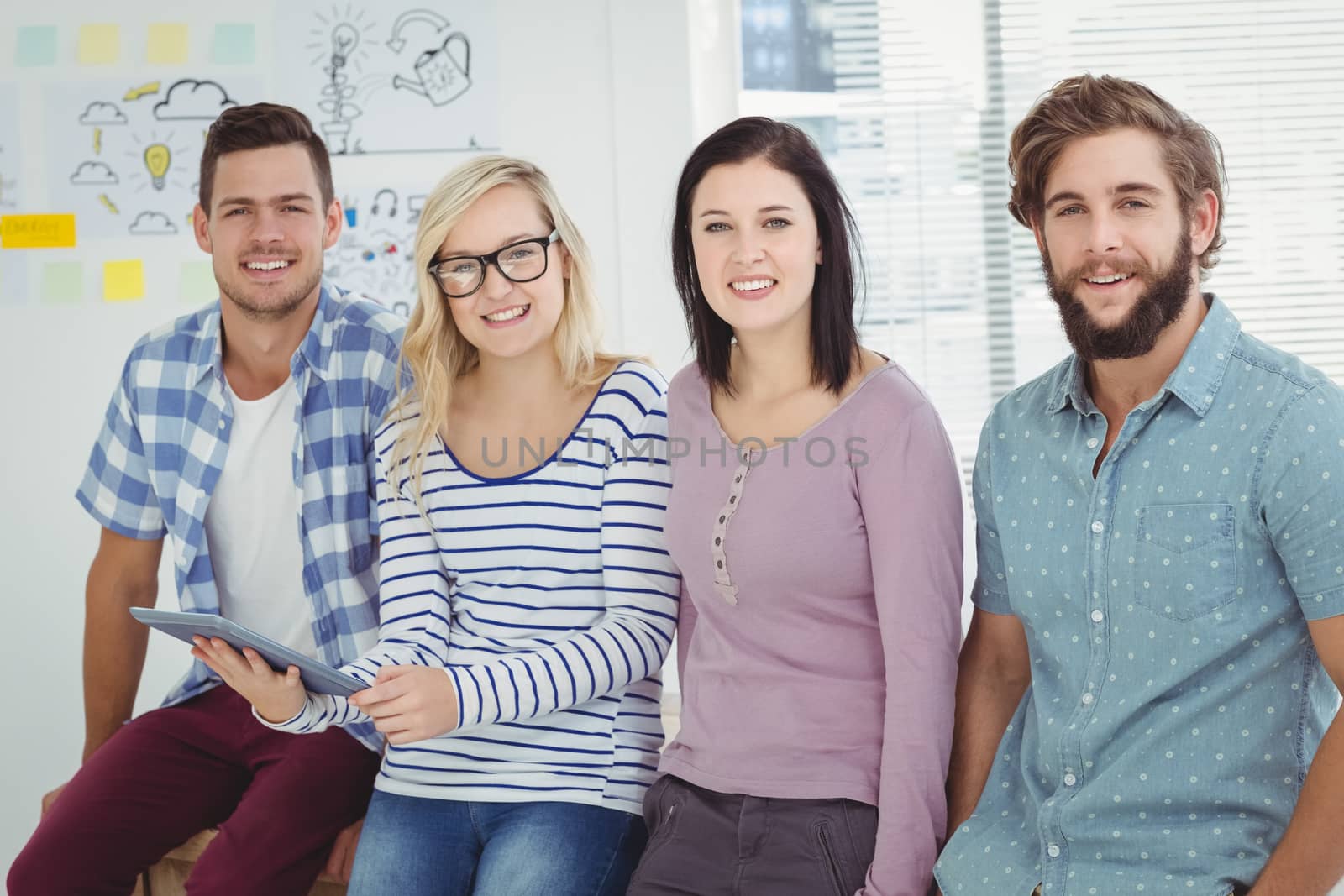 Portrait of happy business people with digital tablet at desk in office