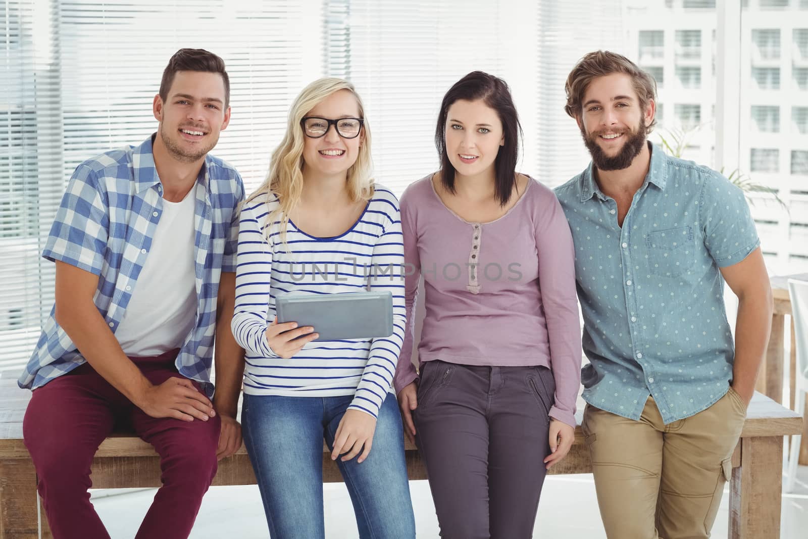 Portrait of smiling business people with digital tablet at desk  by Wavebreakmedia