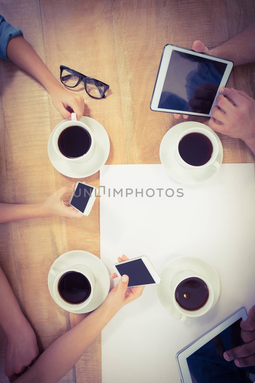 Overhead view of people using technology at desk  by Wavebreakmedia