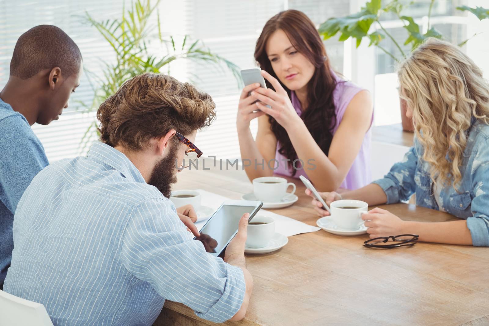 Business professionals using technology while sitting at desk in office