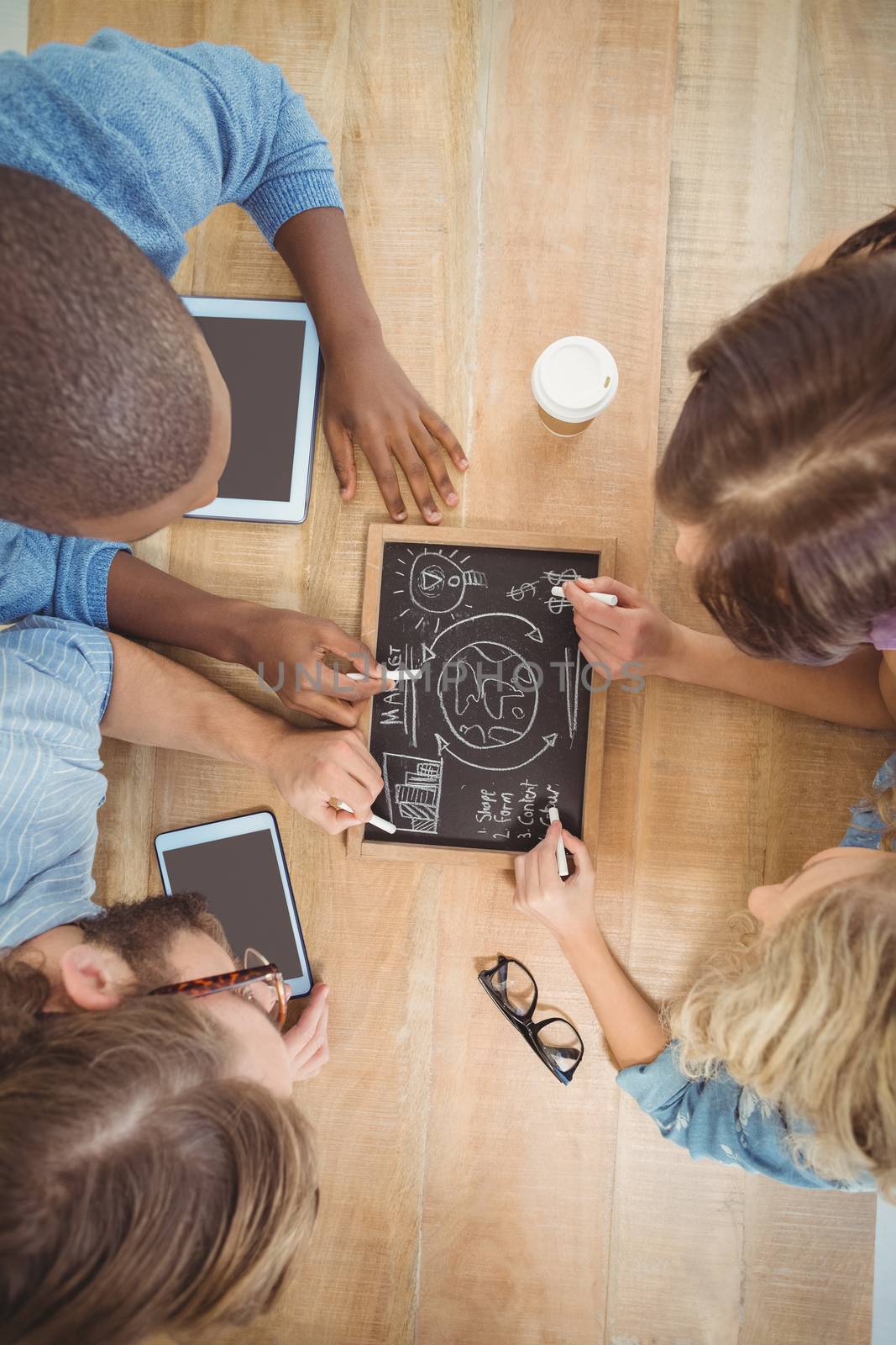 Close-up of people writing business terms on slate at table 