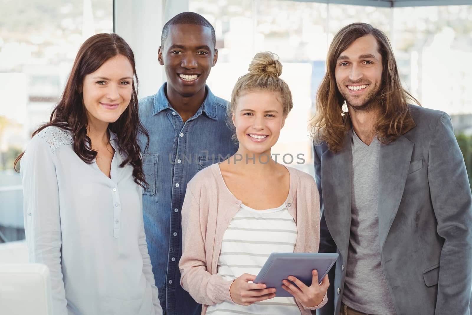 Portrait of smiling business team with woman holding digital tablet at office