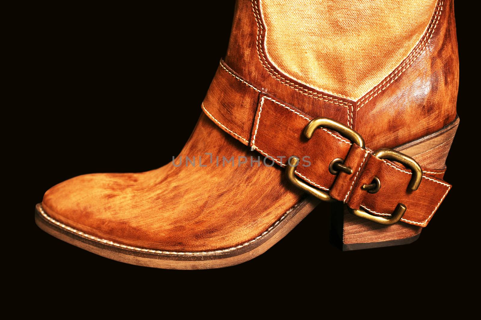 Female boot of the cowboy on a black background