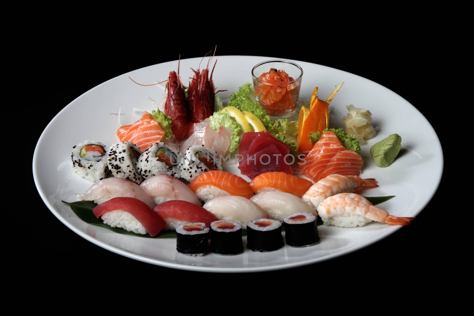 round plate of sushi and sashimi on black background