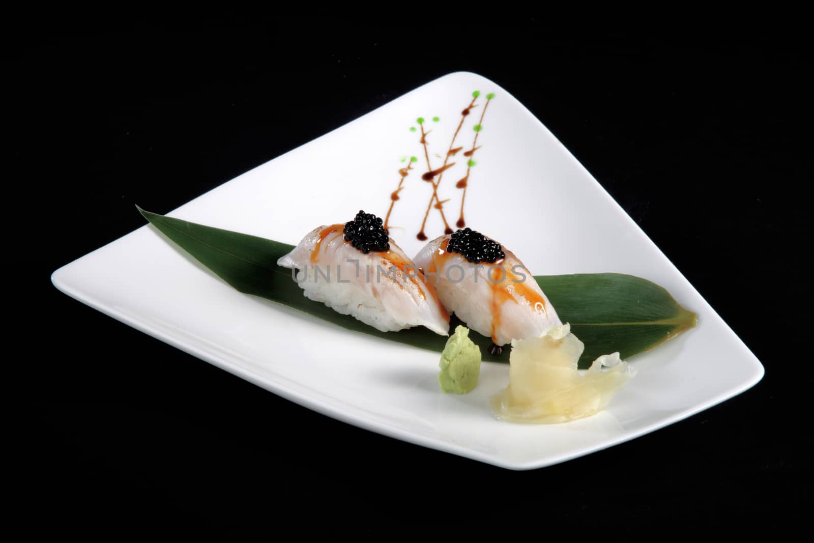 portion of sushi with vegetables on white plate, black background