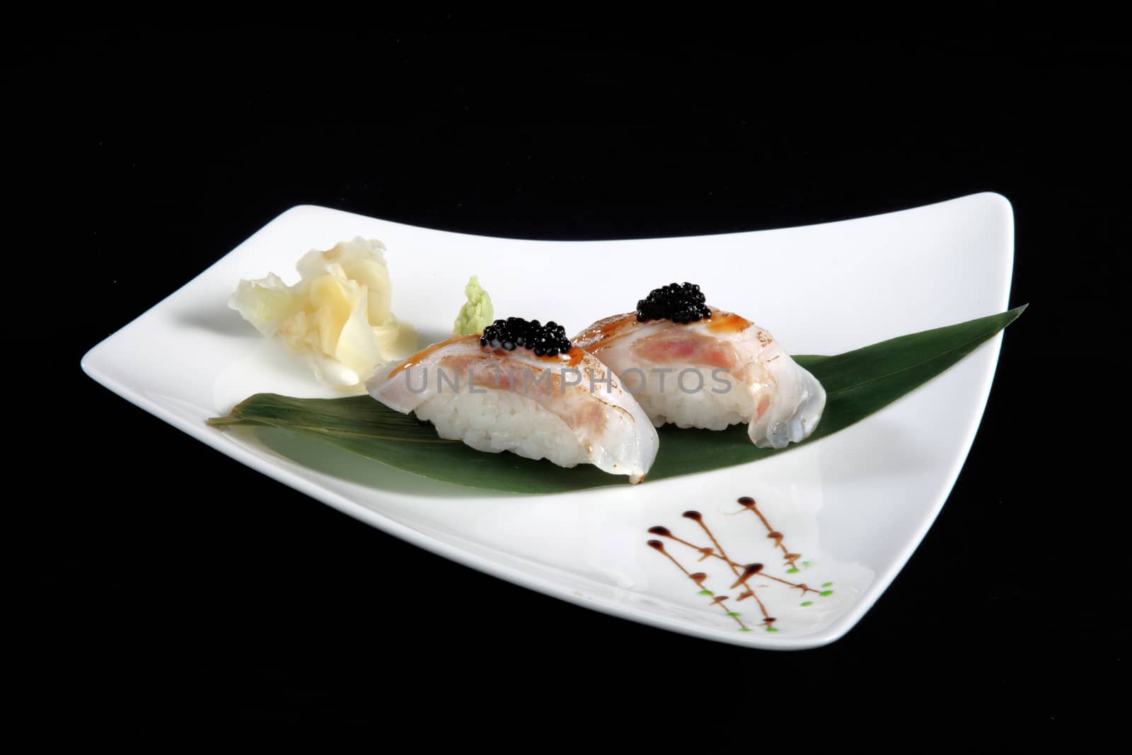 portion of sushi with vegetables on white plate, black background