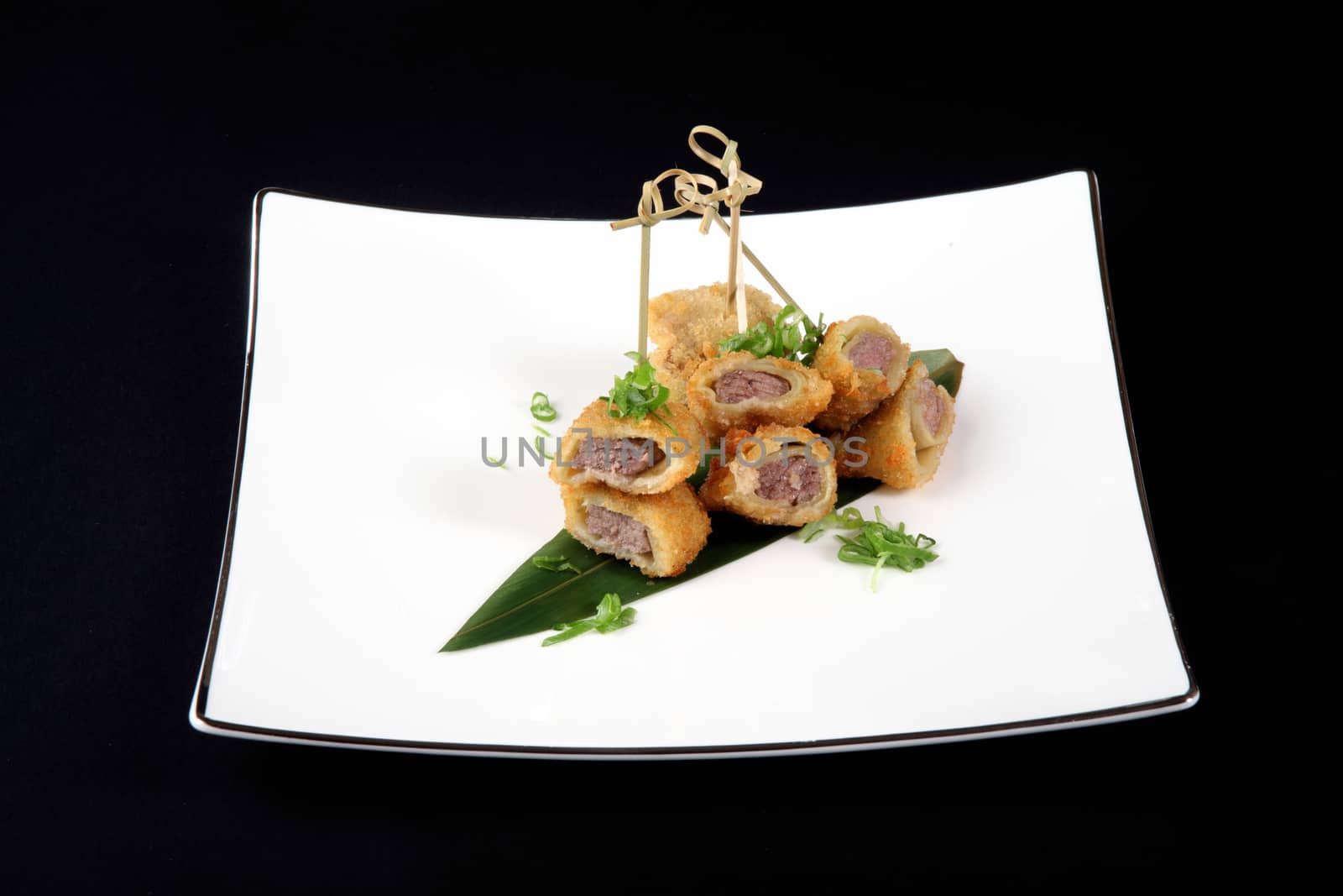 breaded fish with vegetables in white plate on black background