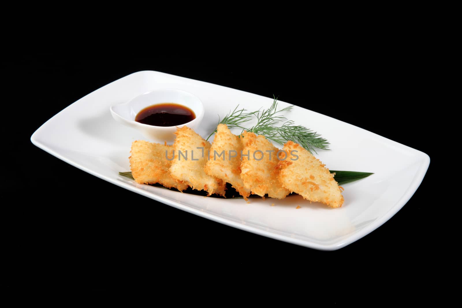 breaded squid in square plate on a black background