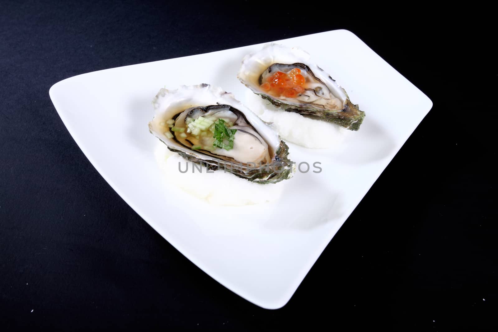 white plate with two oysters on a black background