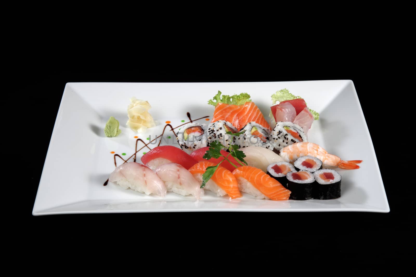 various sushi and sashimi with wasabi on white plate, black background