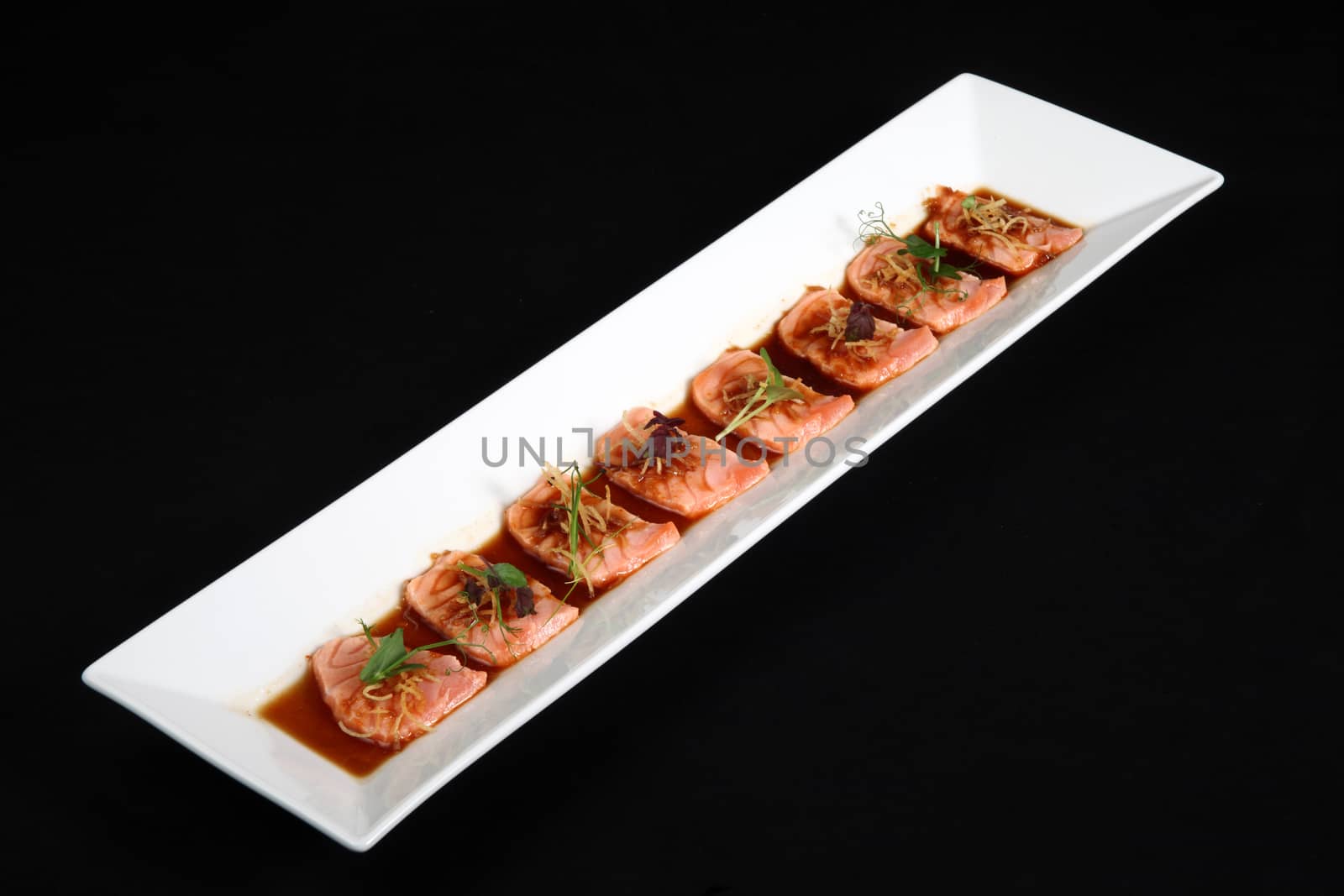 Salmon meat with sauce dish is white on black background