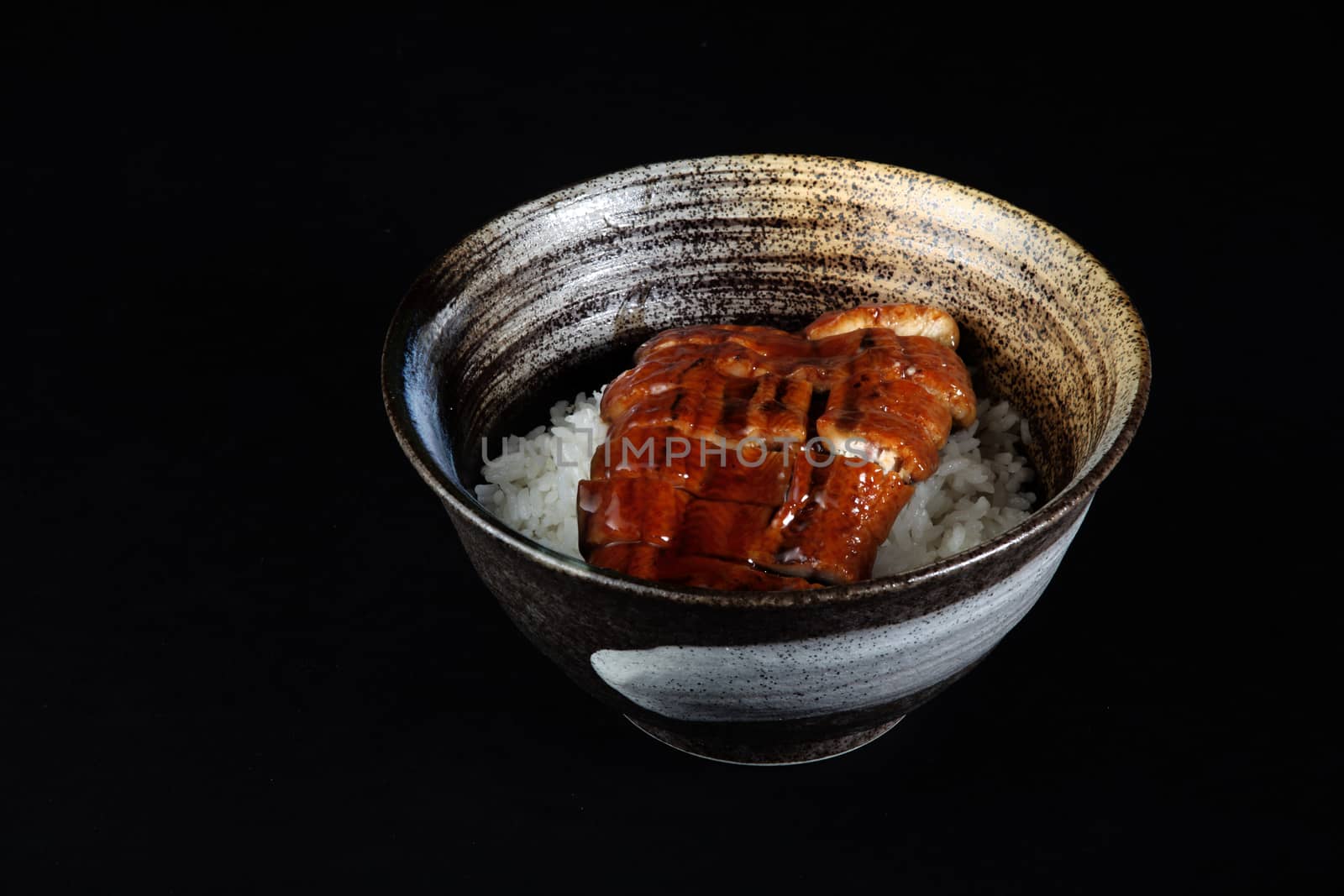 eel meat with rice in bowl on a black background