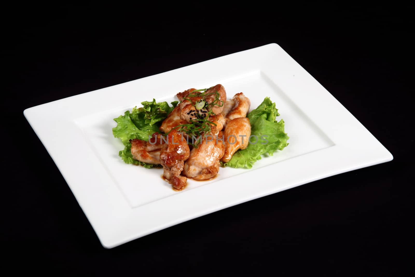 grilled chicken with vegetables in white plate on a black background