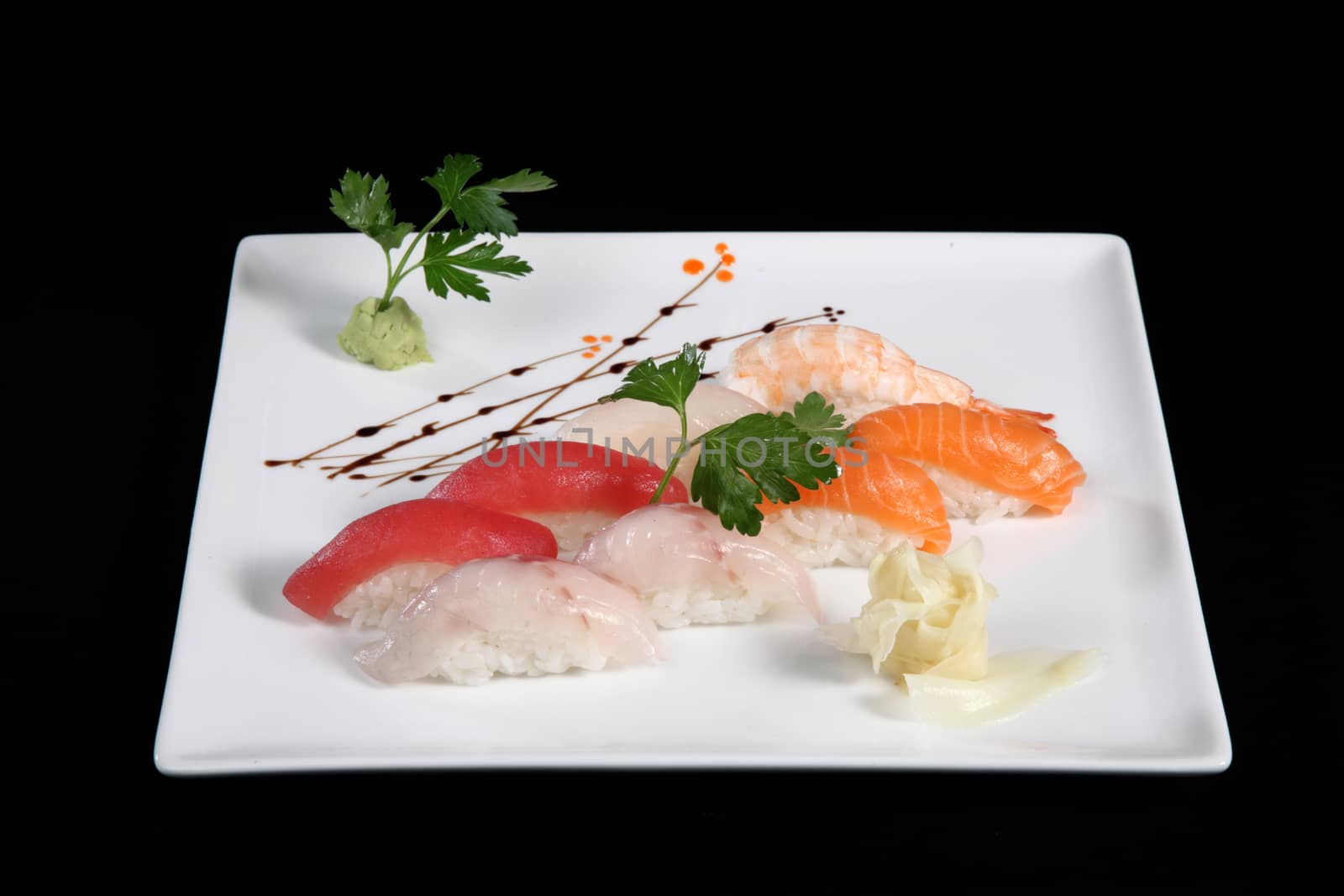 various sushi with wasabi on white plate, black background