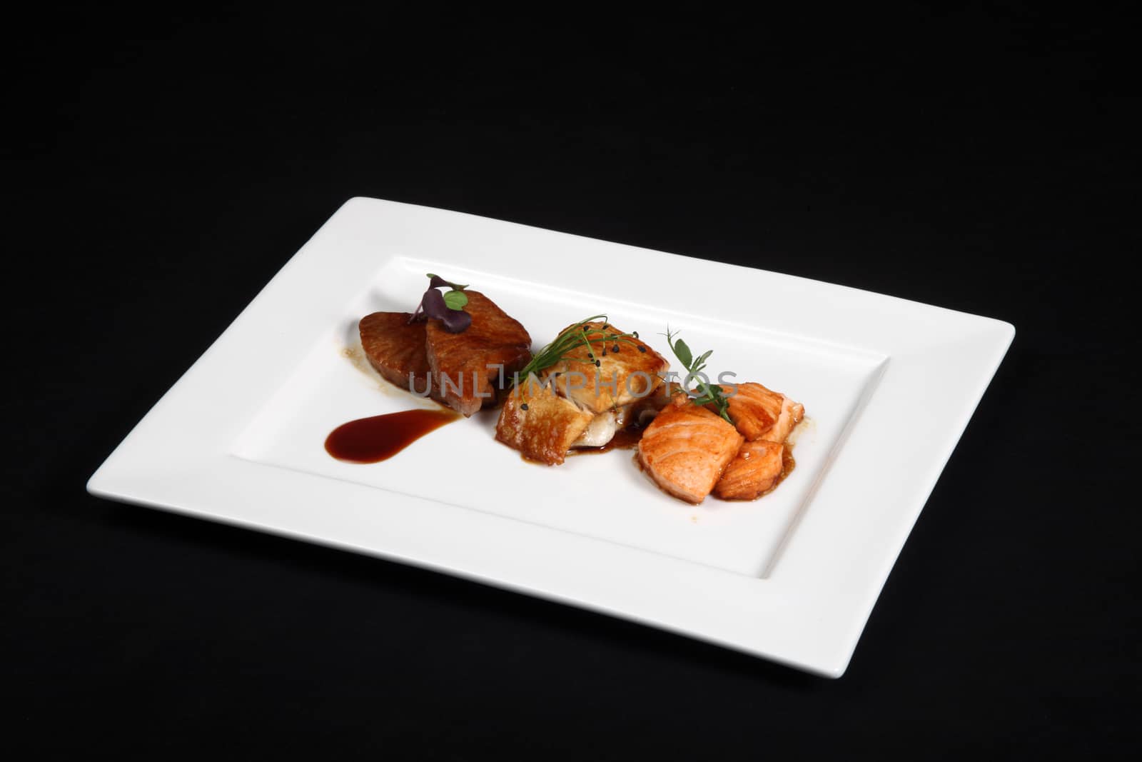 mixed fish grilled in white plate on a black background