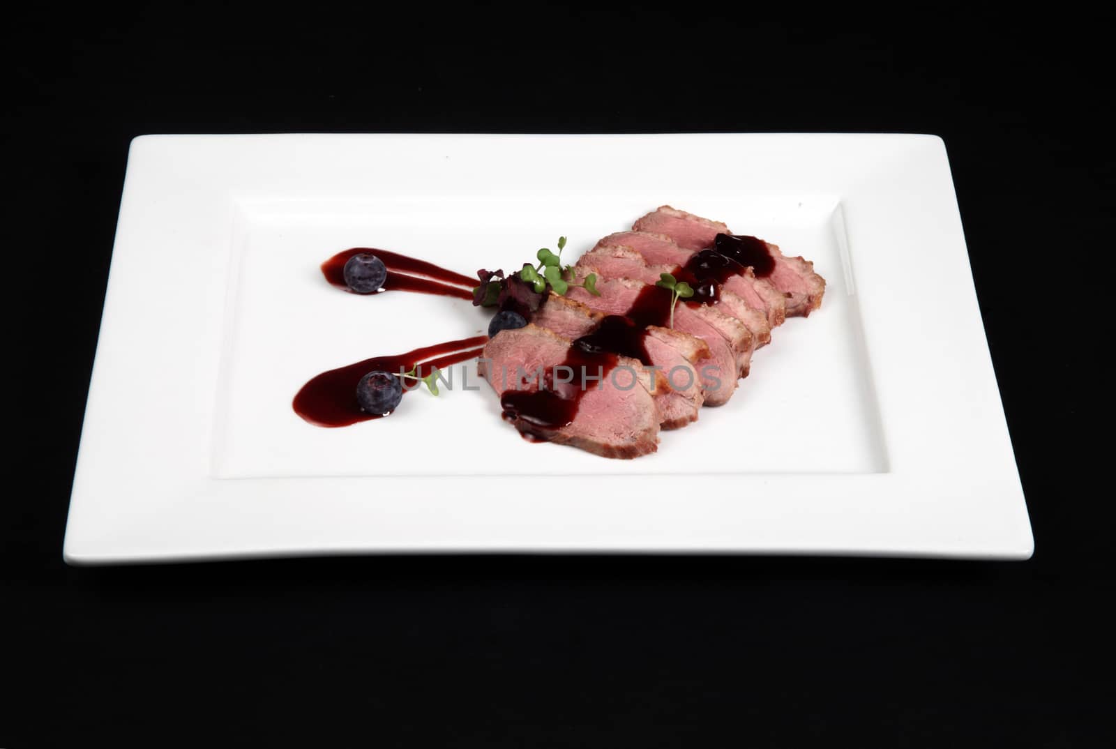 duck meat with cranberry cream in white plate on a black background