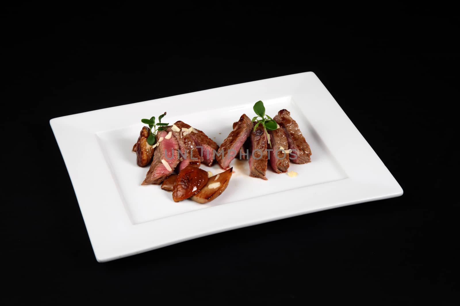 beef with mushrooms in white plate on a black background