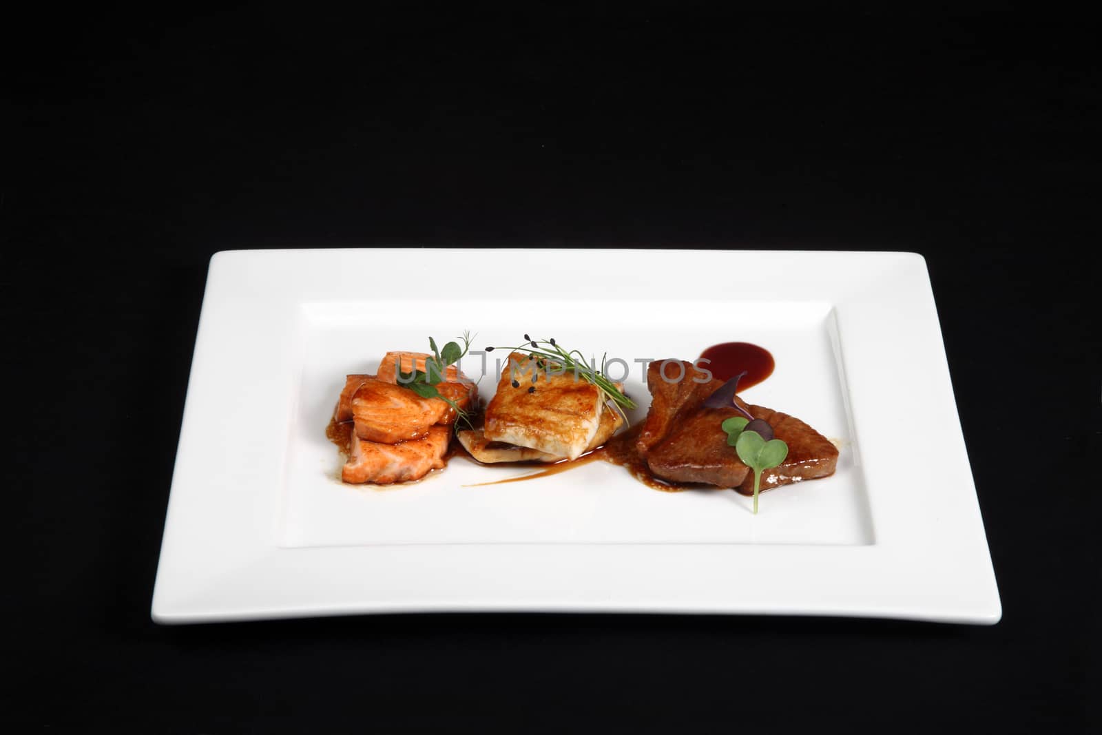 mixed fish grilled in white plate on a black background