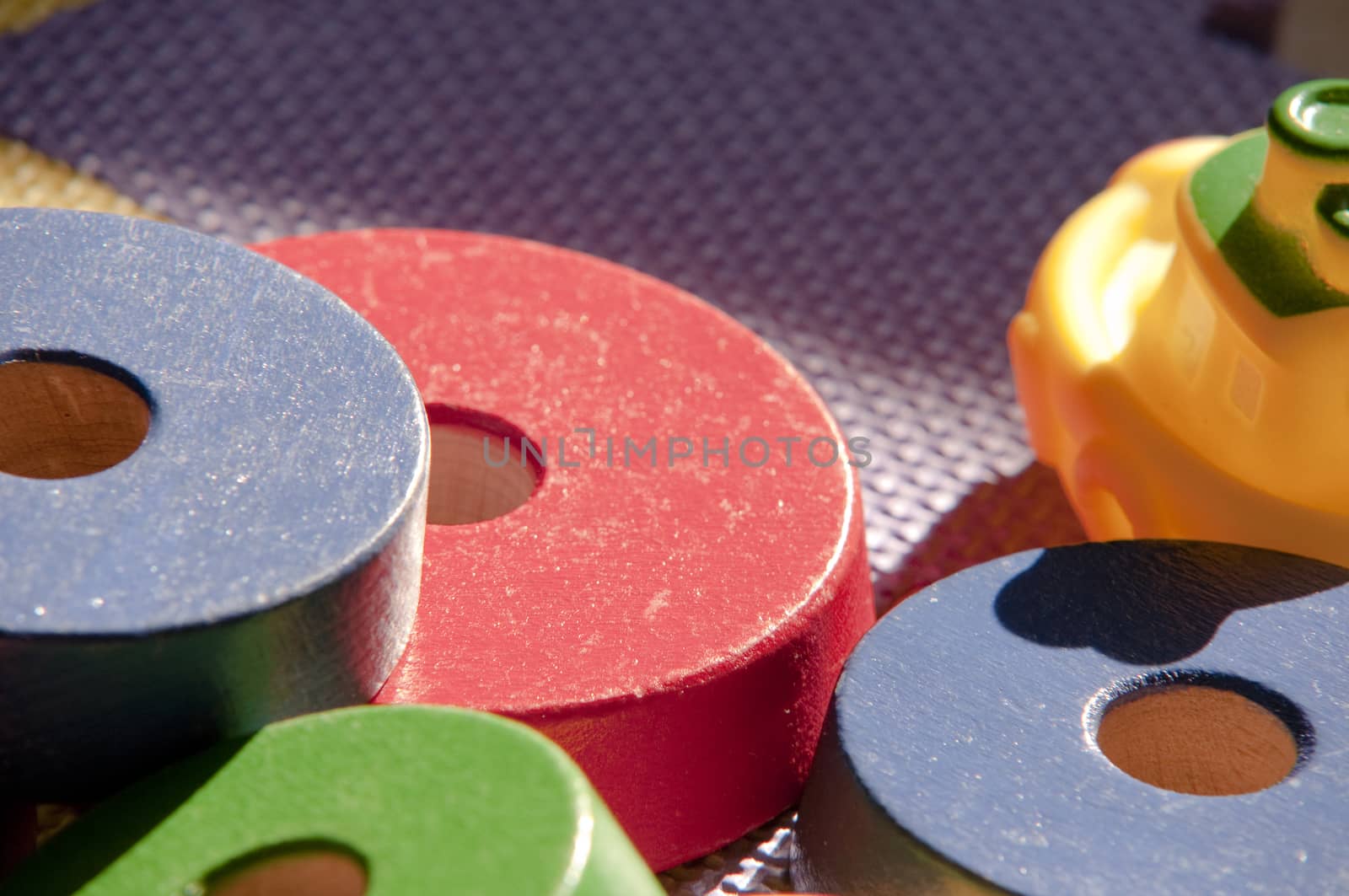 colored carpet for children with toys, a rubber boat and wooden disks on a summer day