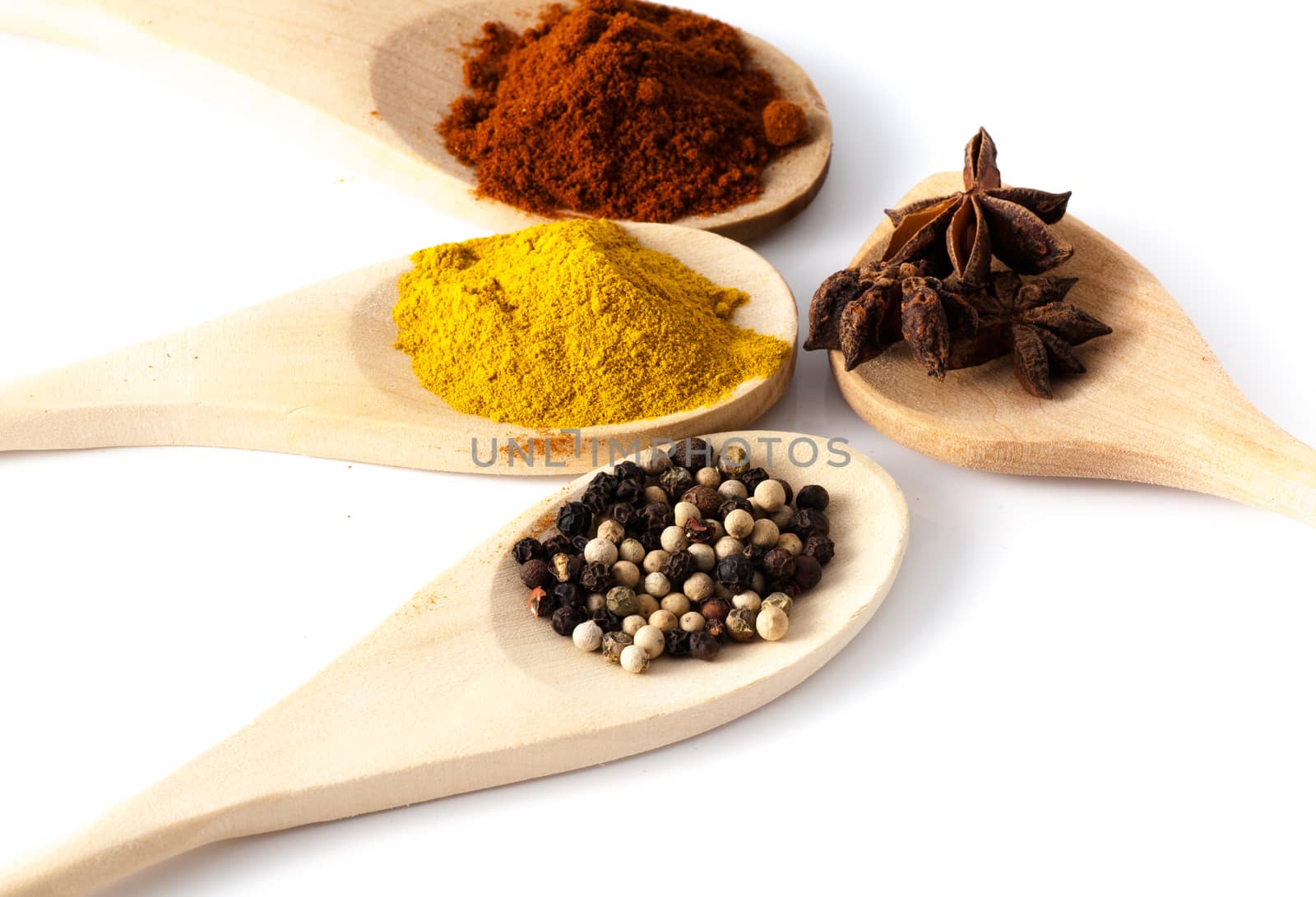 Wooden spoons filled with spices on a white background
