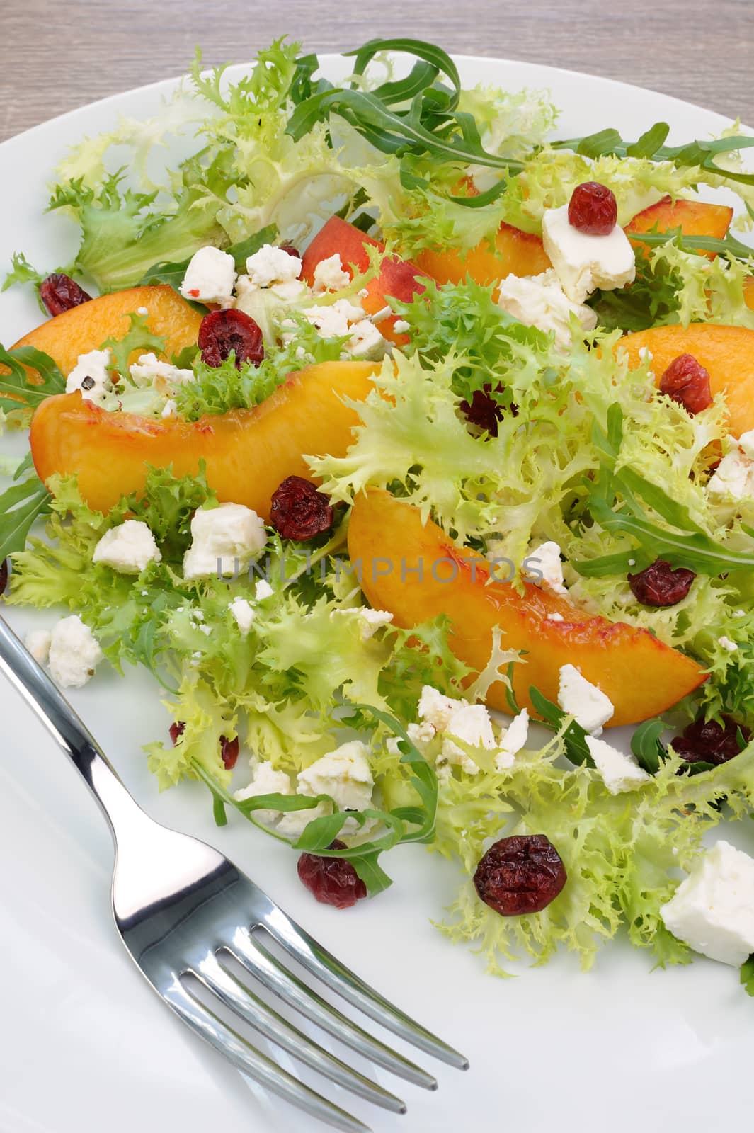 Salad of lettuce and arugula with peaches, feta cheese, cranberries