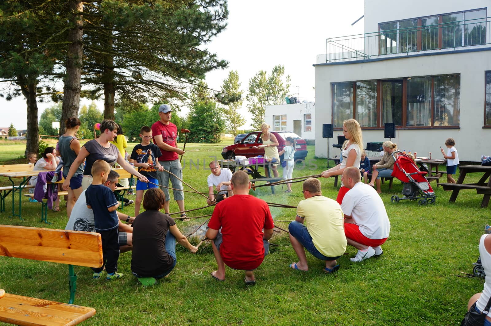 SIANOZETY, POLAND - JULY 22, 2015: People sitting around a fire place and grilling sausages at a barbecue event