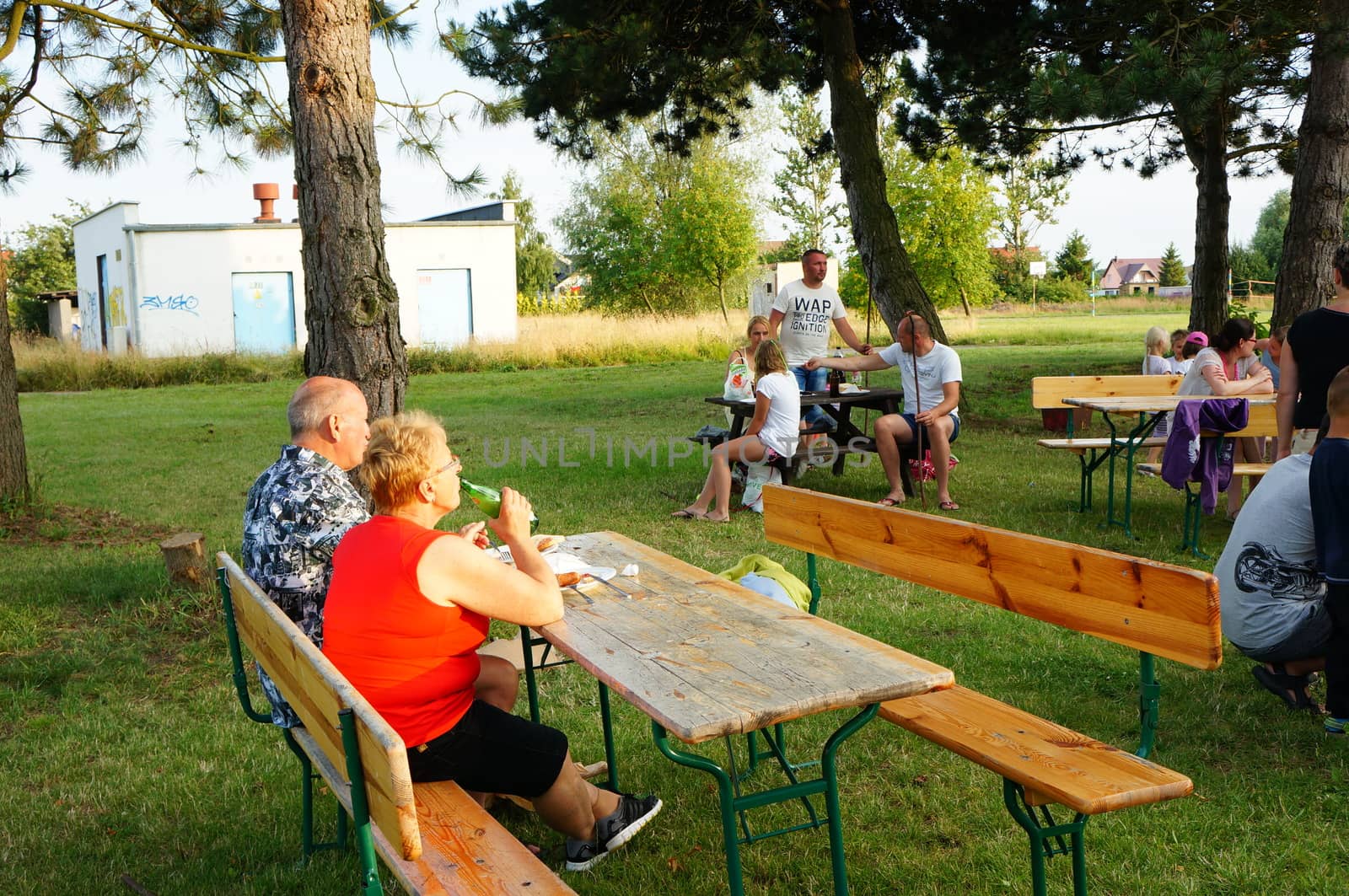 SIANOZETY, POLAND - JULY 22, 2015: People sitting on benches by wooden tables on a barbecue event