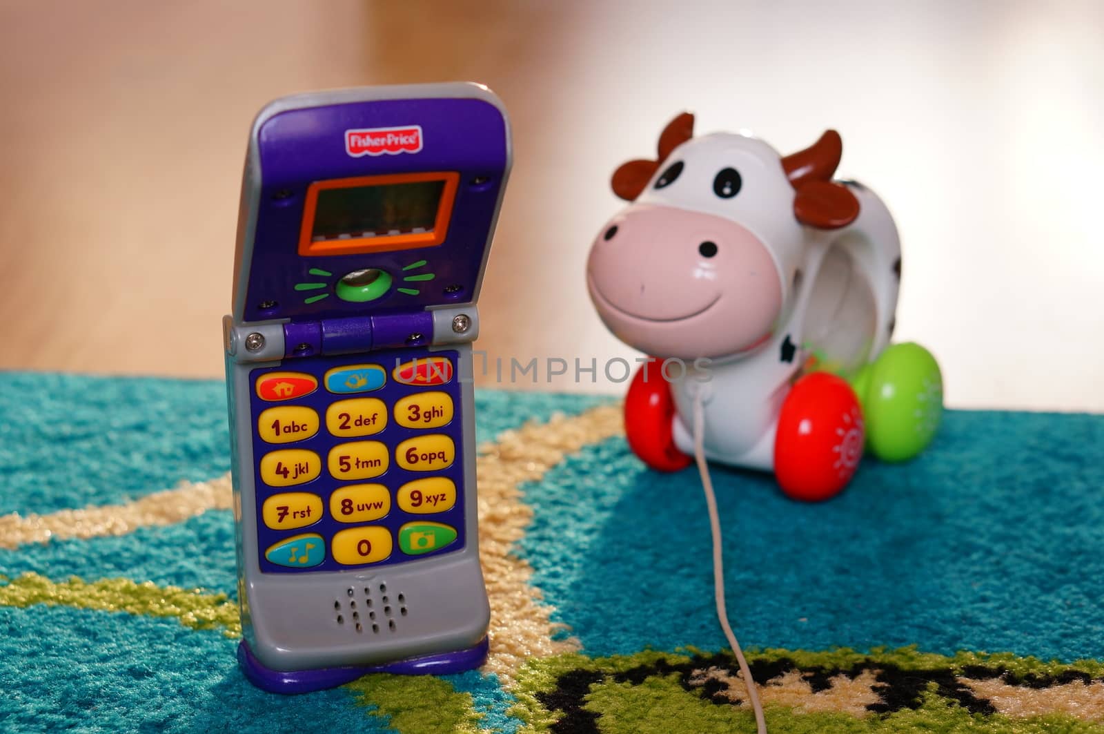 POZNAN, POLAND - AUGUST 20, 2015: Fisher Price plastic toy phone and toy cow in background