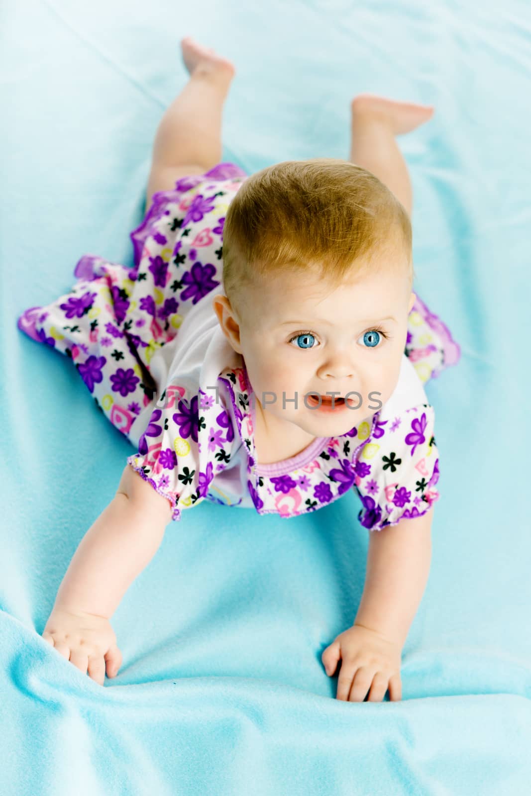 baby girl in a dress creeps on the blue coverlet by pzRomashka