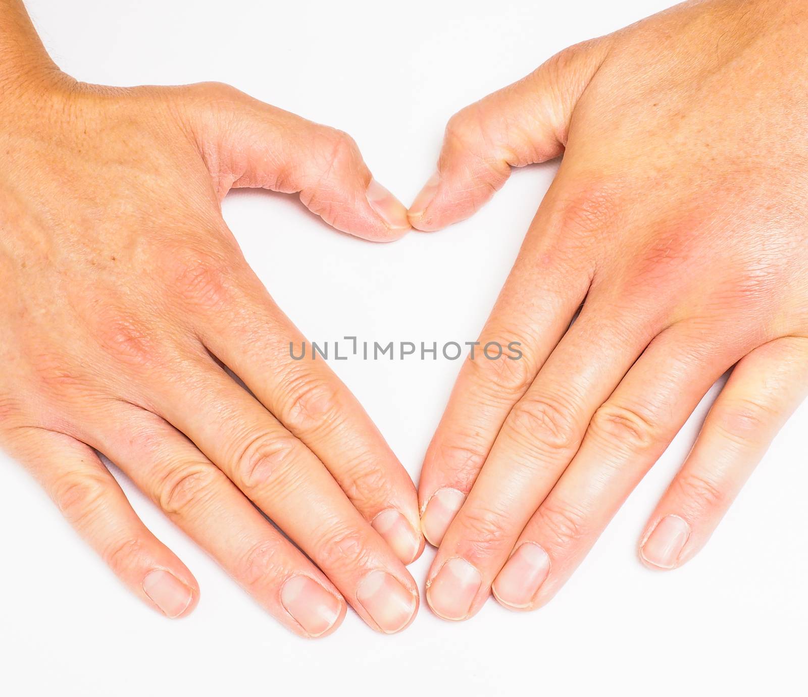 Adult person creating heart with hands towards grey white