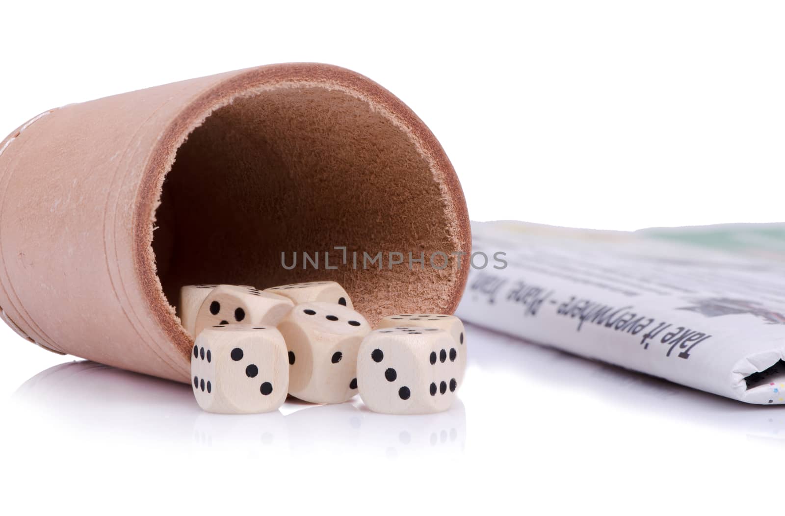 Seven wooden dice on the leather dish and newspaper beside.