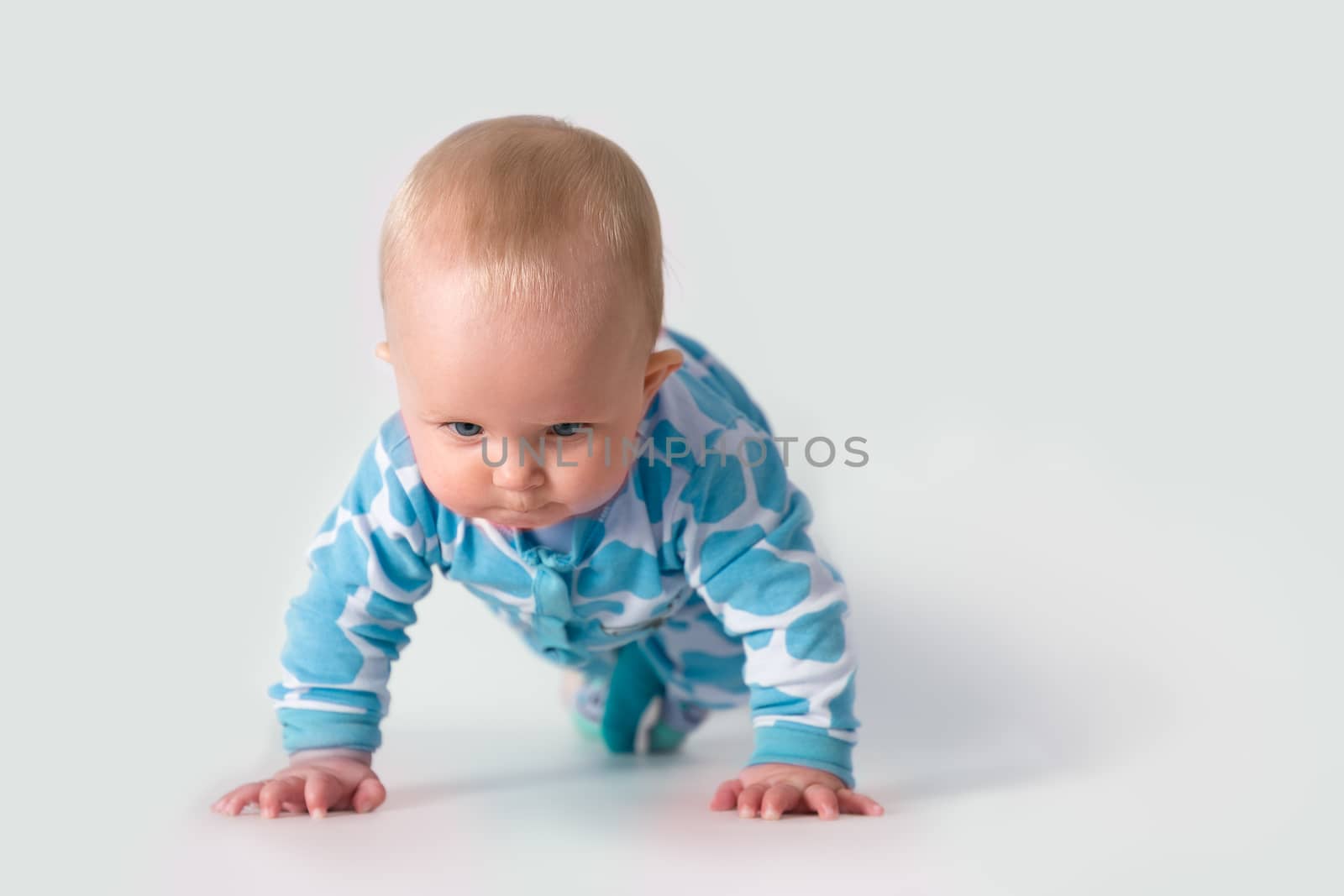 Baby in blue polka pajama concentrating on doing push-ups