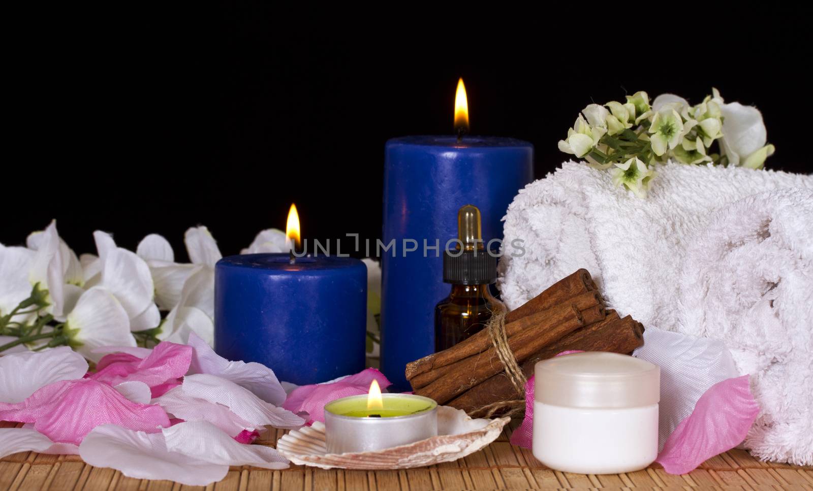 Towels, massage oil and candles on a black background