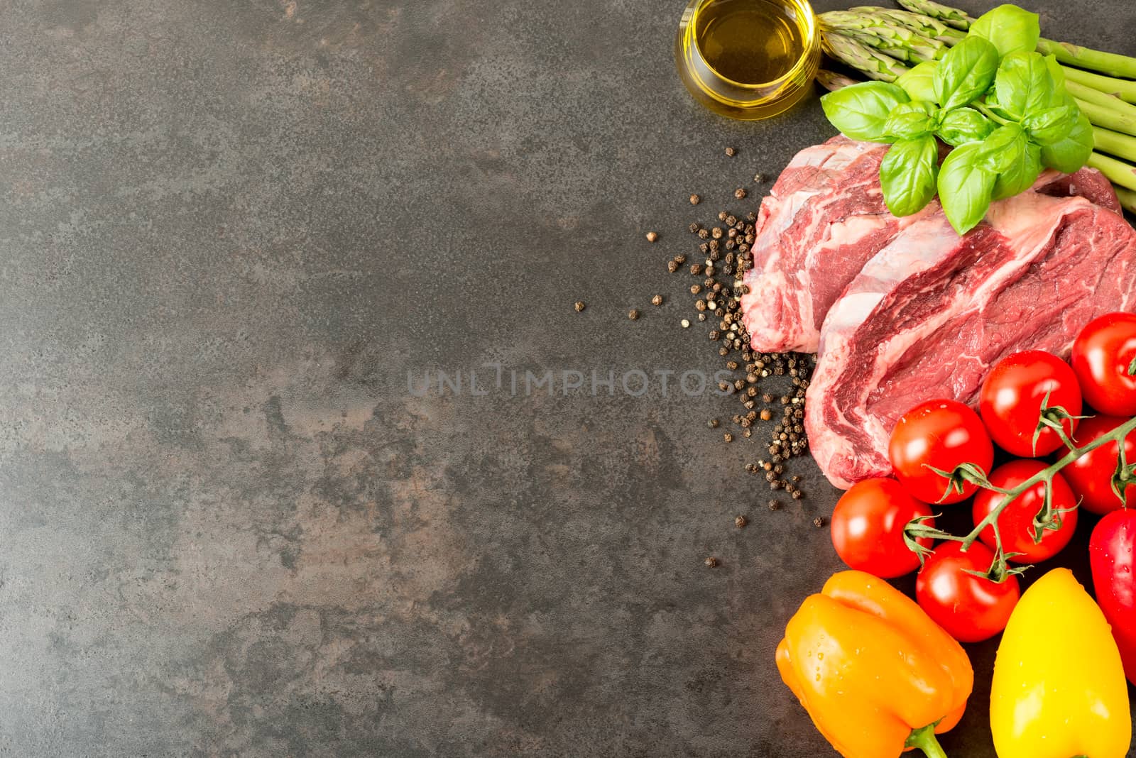 Raw beef steak and vegetables on rustic table with copy space