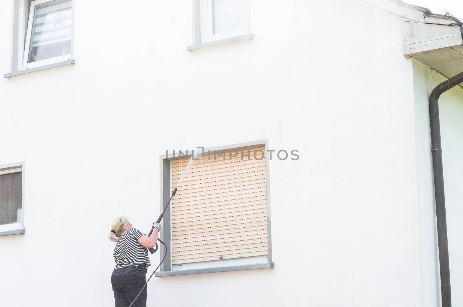 Exterior cleaning and building cleaning a gable wall with high pressure water jet.