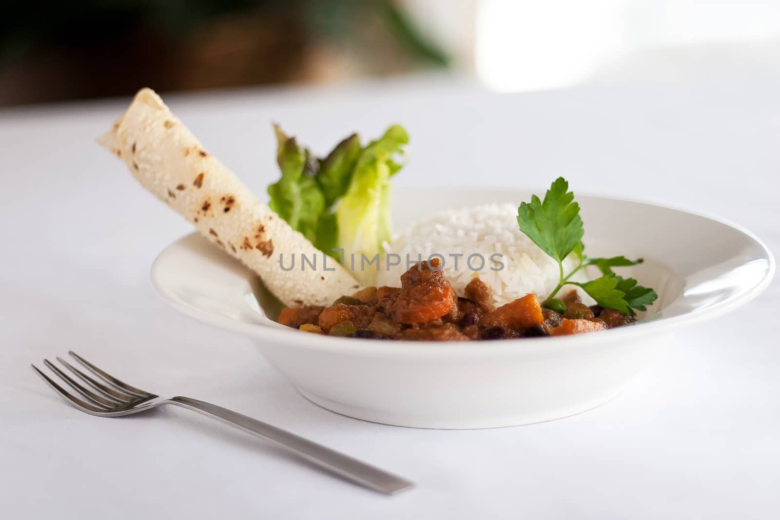 A bowl of Indian vegetable curry with rice and naan