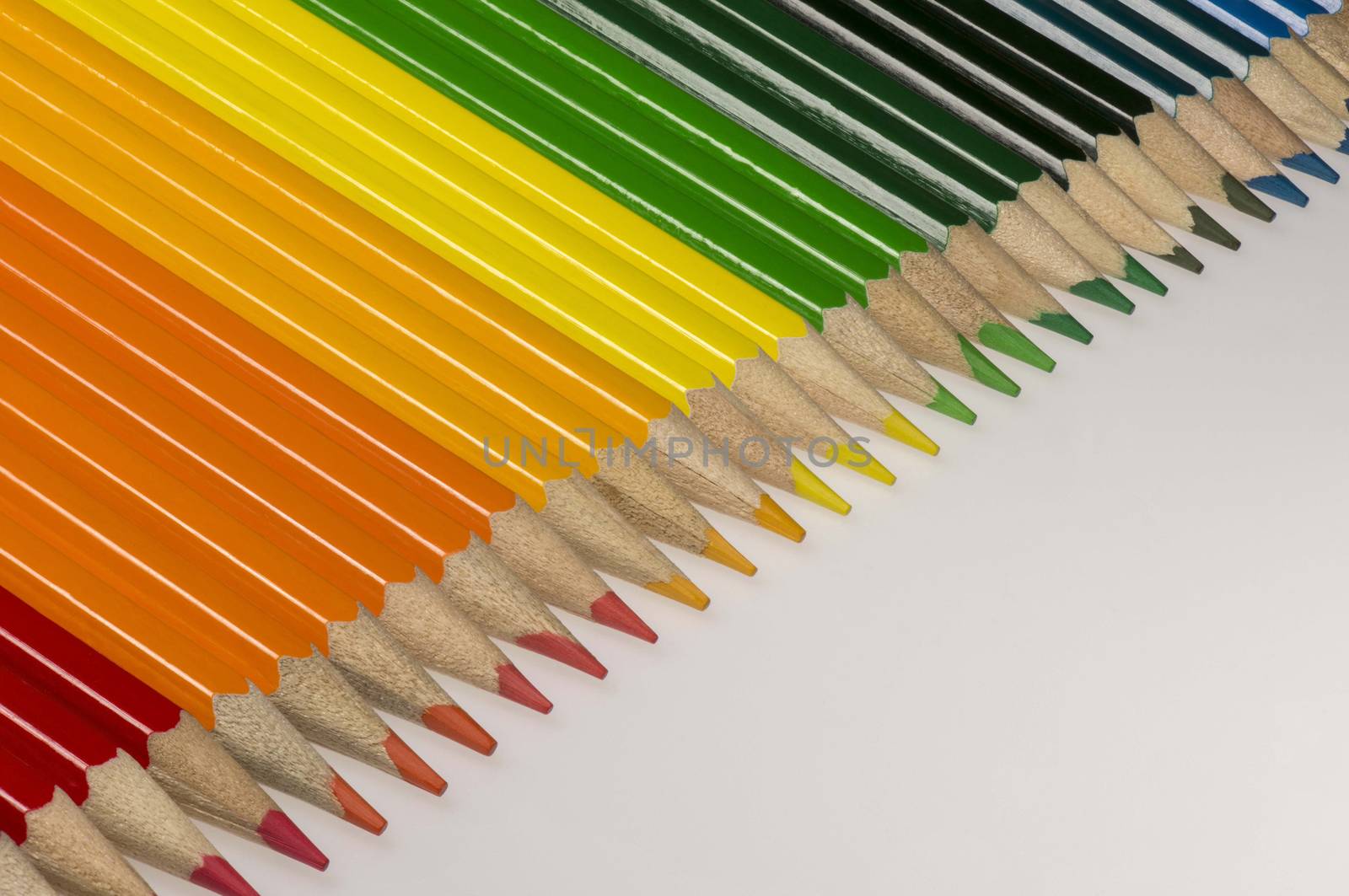 Abstract composition of a set wooden colour pencils against a white background
