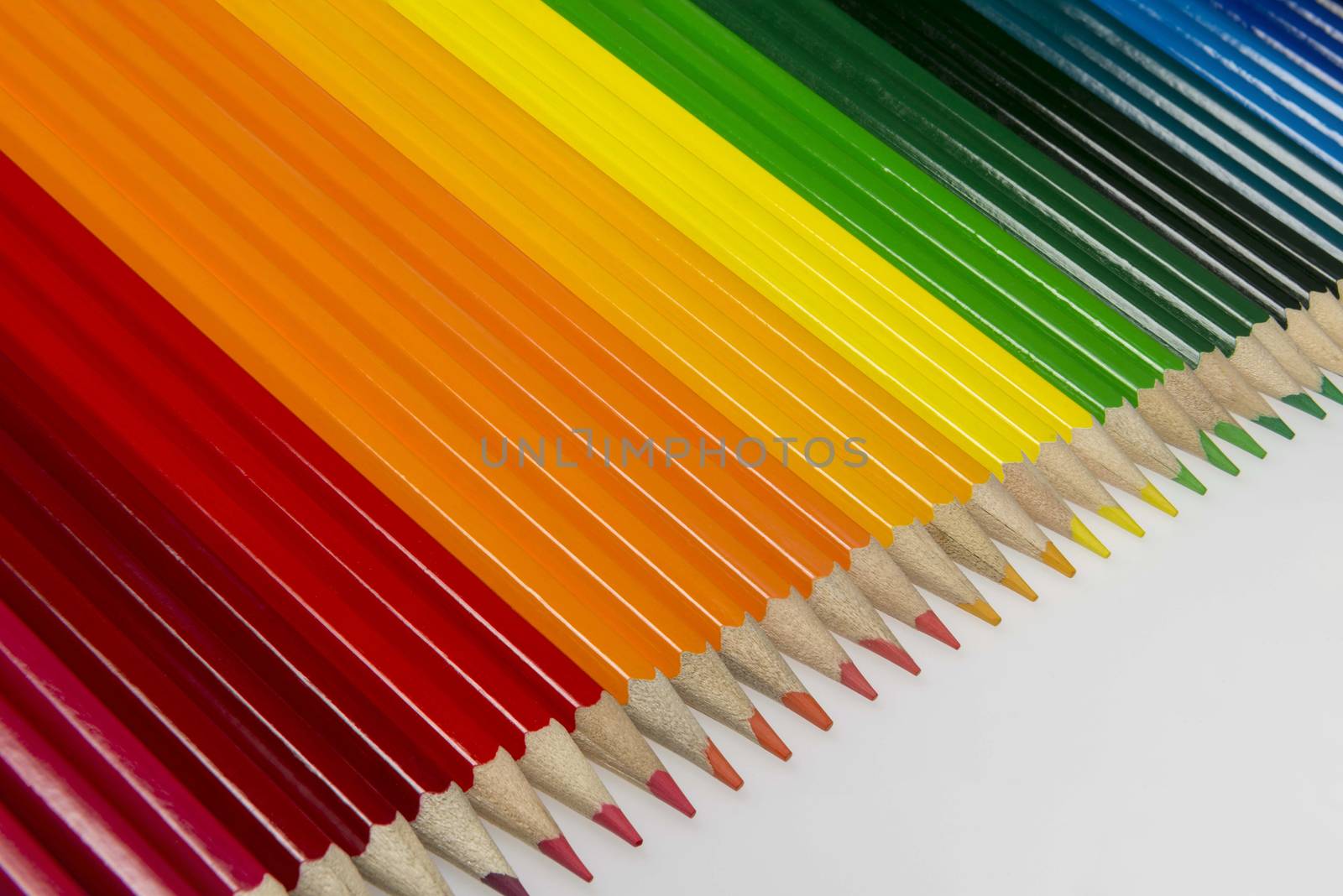 Abstract composition of a set wooden colour pencils against a white background
